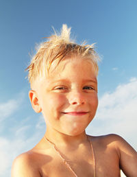 Close-up portrait of smiling boy against blue sky