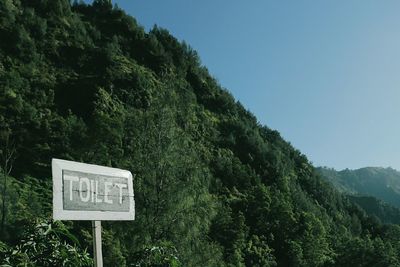 Low angle view of toilet sign against clear sky