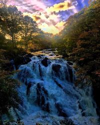 Scenic view of waterfall against sky during sunset