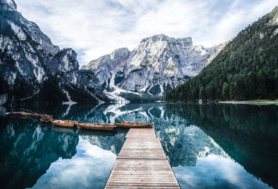 Boats in lake against snowcapped mountains