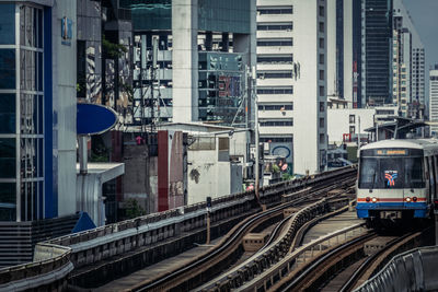 Train on railroad tracks by buildings in city