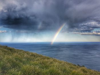 Scenic view of rainbow over sea against sky