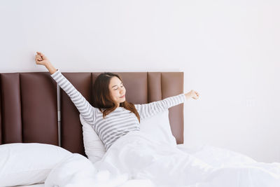 Young woman sitting on bed