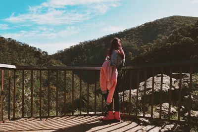 Low section of woman standing on railing against trees