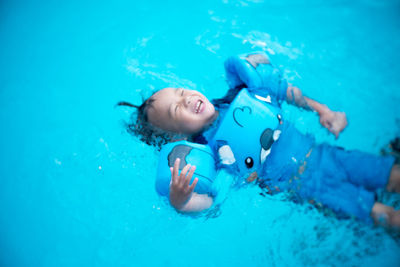 High angle view of cheerful boy swimming in pool