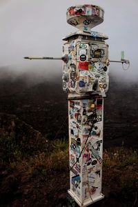 Close-up of information sign on field against sky