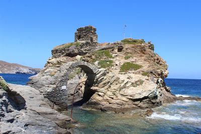 Rock formations in sea against clear blue sky