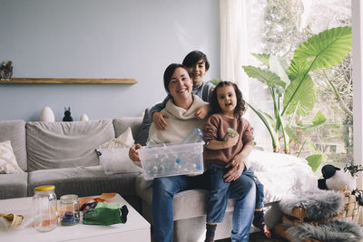 Portrait of cheerful family with plastic waste sitting in living room at home