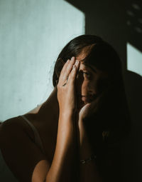 Portrait of young woman sitting against wall