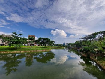 Scenic view of lake by trees and building against sky