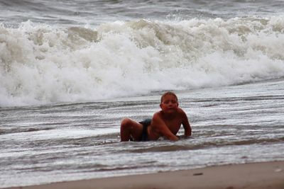 Full length of shirtless boy in sea