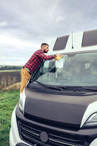 Man cleaning windshield of car