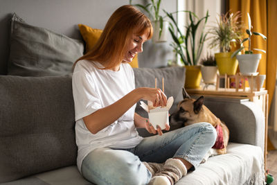 Young woman sitting on sofa at home