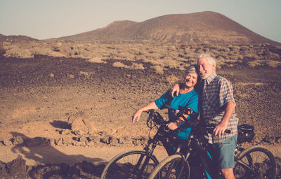 Portrait of smiling couple with bicycles standing on land 