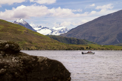 Small boat on a lake with a snow-capped mountain in the background on a sunny day.