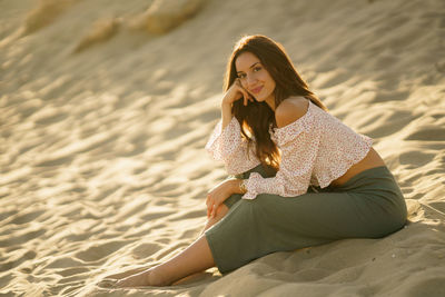 Young woman sitting on sand at beach