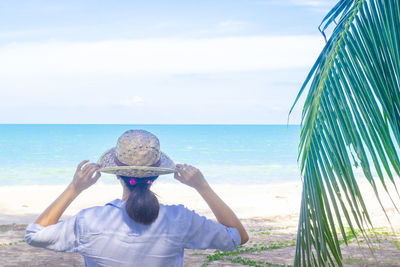 Rear view of man on beach against sky