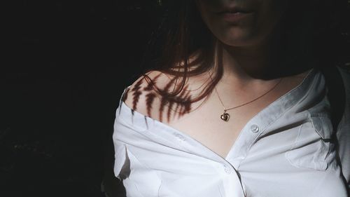 Close-up of teenage girl wearing gold necklace in darkroom