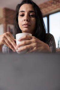 Portrait of young woman using mobile phone at home