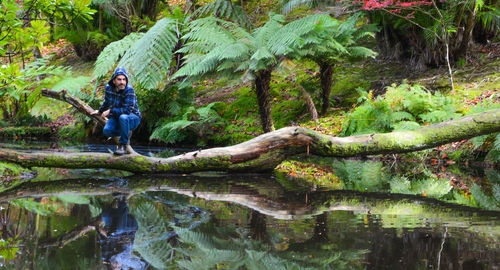 Reflection of man in lake amidst trees in forest