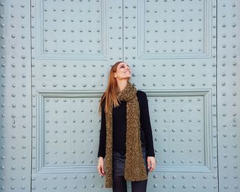 Young woman looking away while standing on wall / happy woman smiling