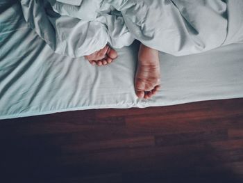 Low section of child sleeping on bed