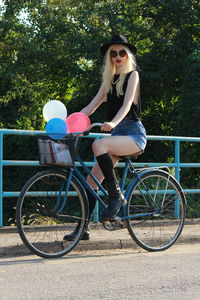 Portrait of woman with bicycle against trees