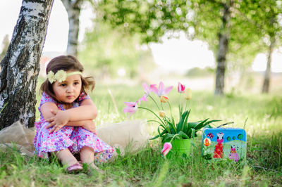 Portrait of happy girl sitting on tree trunk