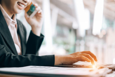 Midsection of woman using smart phone on table