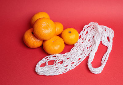 Eco-friendly mesh with tangerines on a red festive background. feast of the nativity of christ.