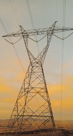 Low angle view of electricity pylon against sky during sunset