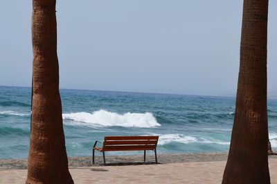 Chair on beach against clear sky