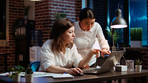 Female friends using laptop at table