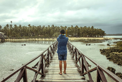 Rear view of man standing on pier