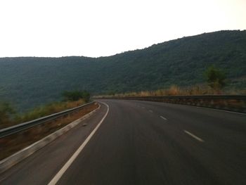 Road by mountains against clear sky