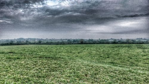 Scenic view of grassy field against cloudy sky