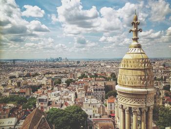 Aerial view of city buildings against cloudy sky