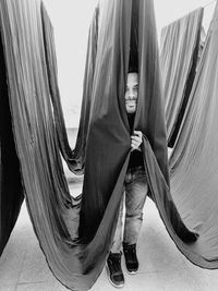 Portrait of man standing amidst curtains