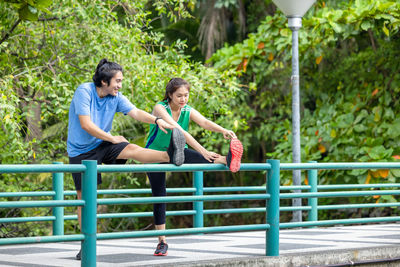 Full length of couple sitting on railing