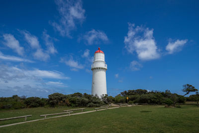 Lighthouse by building against sky