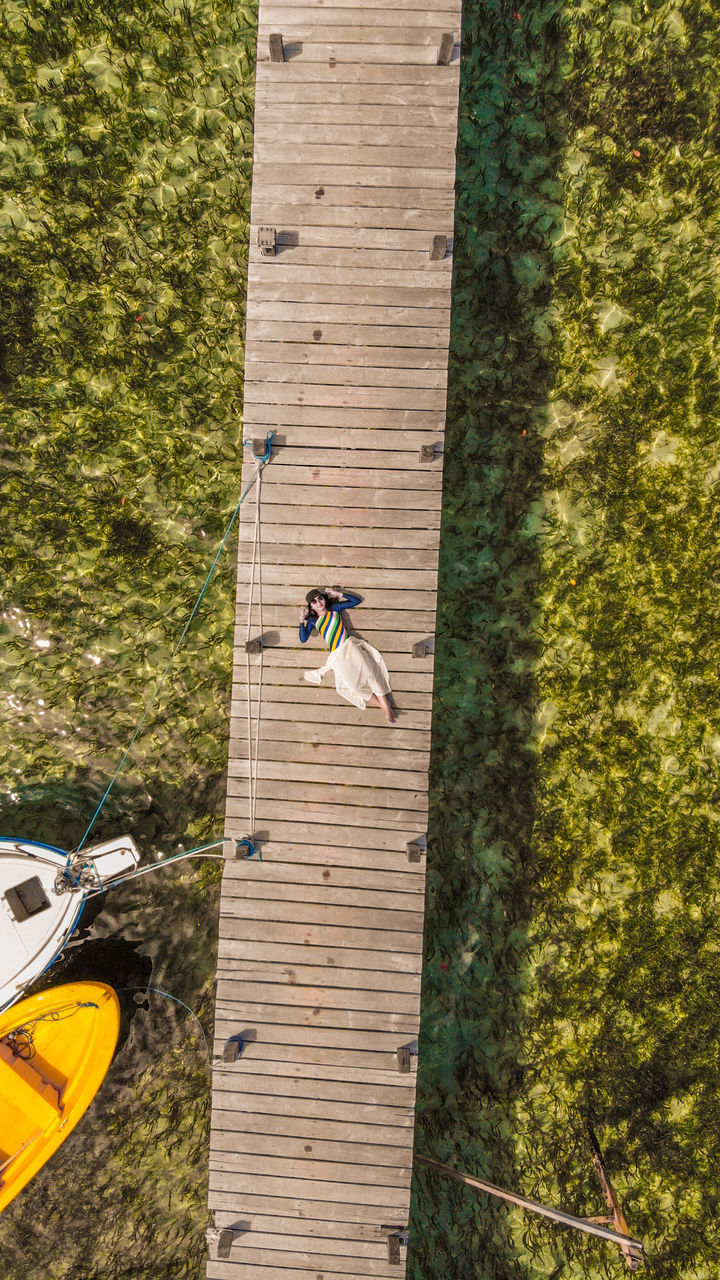 HIGH ANGLE VIEW OF MAN CLIMBING ON TREE TRUNK