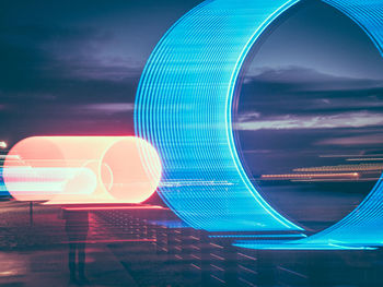 Digital composite image of illuminated ferris wheel against sky at night