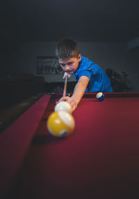 Boy aiming cue ball while playing pool