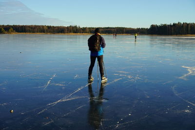Rear view of man skating on frozen lake during winter