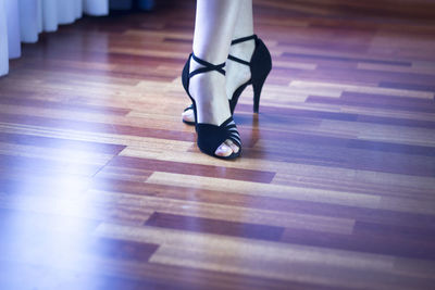 Low section of woman standing on hardwood floor