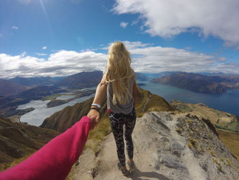 Rear view of woman standing on mountain against sky