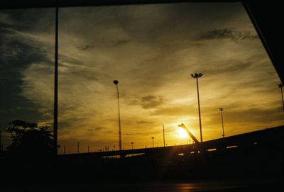 Low angle view of silhouette street lights against sky during sunset