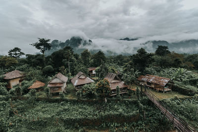 Houses and trees on field against sky