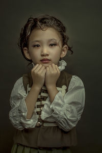 Portrait of a girl standing against black background