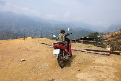 Rear view of boy sitting on motorcycle